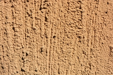 Construction, repair work, lining, covering walls with the latest materials. Brown wide background with voluminous granules, drops, textured sand on the street wall.