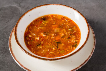 Hot and sour Asian soup with vegetables in white bowl