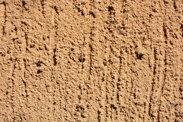 Construction, repair work, lining, covering walls with the latest materials. Brown wide background with voluminous granules, drops, textured sand on the street wall.