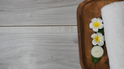 Spa-like setting with candles, flowers, and towel  Relaxing spa setup with towels and candle on marble tray in tranquil setting, copy space on the right