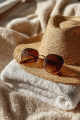 Straw hat and sunglasses on folded towel. Concept of summer vacation, travel and beach relaxation