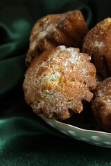 Delicious homemade muffins sprinkled with powdered sugar on green velvet