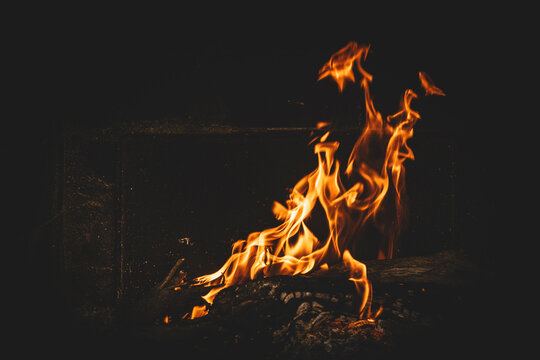 Bright orange flames rising from a wood vine barbecue fire, glowing and crackling with natural warmth