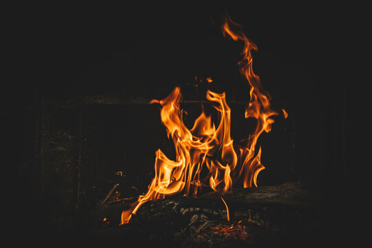 Bright orange flames rising from a wood vine barbecue fire, glowing and crackling with natural warmth