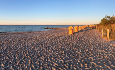 Beach with wicker chairs and sunset light on German coast