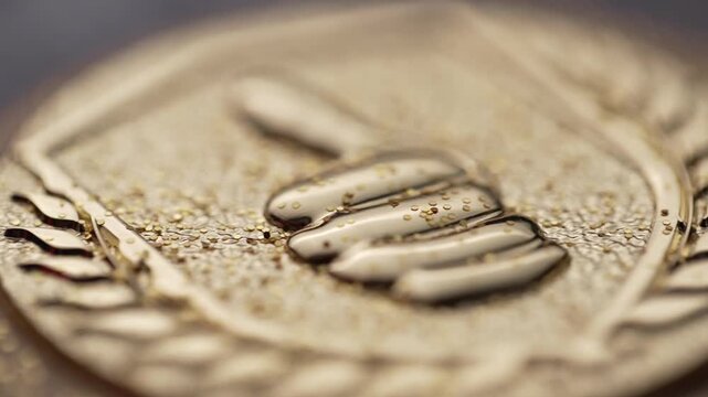 Close-up of a golden medal featuring embossed hand gesture pattern with detailed texture