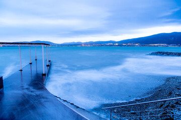 Storm in Gelendzhik on long exposure. Waves in form of fog run into beach of Gelendzhik. Pier....