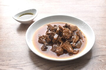 slice braised pork stew in herb brown soup dipping chili and sour sauce on plate