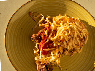 Homemade pasta with meat and tomato sauce in a yellow plate