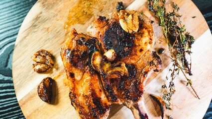 A single perfectly grilled, golden brown pork chop resting on a rustic wooden board. Juicy,...