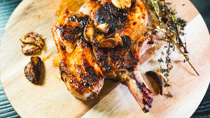 A single perfectly grilled, golden brown pork chop resting on a rustic wooden board. Juicy,...