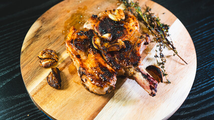 A single perfectly grilled, golden brown pork chop resting on a rustic wooden board. Juicy,...