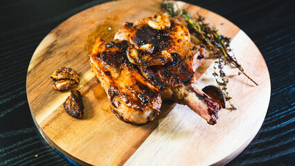 A single perfectly grilled, golden brown pork chop resting on a rustic wooden board. Juicy, beautifully presented, ideal for food blogs and menus.