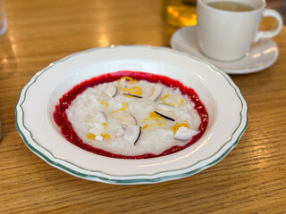 White porridge with coconut, lemon zest, and berry sauce served in a plate. Breakfast, nutrition and balanced healthy eating with hot drink.