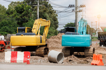 A large excavator is parked in the area of ​​a road construction project and a large water pipe...