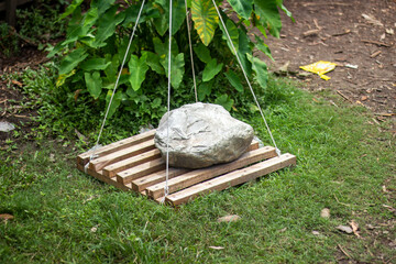 A large rock is suspended by wires above a wooden platform