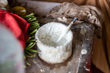 A small white bowl with a spoon inside, possibly for spices or condiments