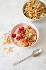 vertical photo of still life Granola with yogurt and raspberries in a bowl