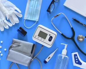 Top view of essential medical diagnostic instruments and personal protective equipment for health monitoring and prevention on a blue background