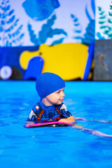 Joyful child in pool float. Young child in a blue swim cap enjoys playing with a float in a bright, colorful swimming pool environment.