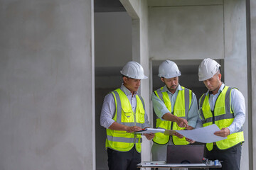 Group of Asian construction engineers discussing building plans at construction site, focusing on teamwork, site inspection, collaboration, civil engineering, and project management.
