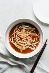 Overhead view of spicy noodle soup in a white bowl