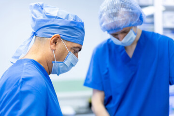 Surgeons in scrubs at work. Two surgeons in blue scrubs focus on a surgical procedure in an...