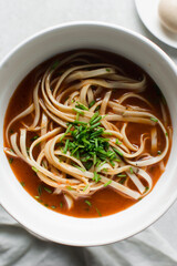 Overhead view of spicy noodle soup in a white bowl
