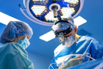 Surgery in a modern OR. Two medical professionals focus on a surgical procedure under bright...