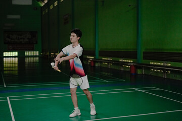 young man making service in badminton court