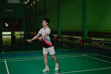 young man making service in badminton court
