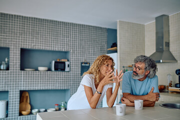 Happy mature couple sharing a warm conversation over coffee in their modern kitchen, enjoying moments of connection and togetherness