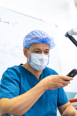 Provider looks at phone at work. A healthcare worker in a blue scrub suit looks at his phone while...