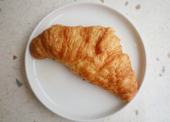 Plate with one fresh croissant on white marble  table