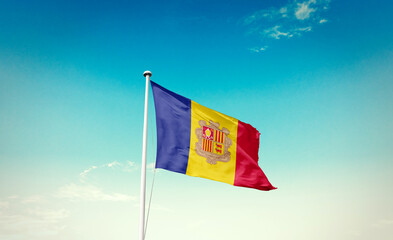 Andorra national flag waving in blue sky.