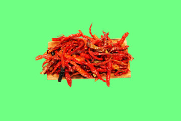 Naklejka premium Dried chili pepper, chillies spicy served on wooden plate. Isolated on green background 