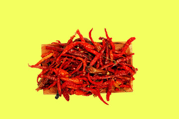 Dried chili pepper, chillies spicy served on wooden plate. Isolated on yellow background 