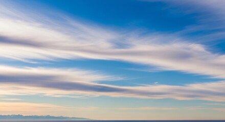 Fototapeta premium Wispy Cirrus Clouds Paint a Serene Sky Above a Distant Mountainous Horizon and Calm Ocean