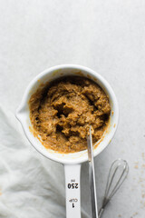 Overhead of peanut butter sauce being mixed in a ceramic cup, process of making creamy savory peanut sauce