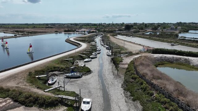 Survol d'un port de plaisance &agrave; mar&eacute;e basse sur l'Ile-de-R&eacute; en France. Bateaux amarr&eacute;s &agrave; des pontons au bord d'un &eacute;tang int&eacute;rieur. Tourisme et nature