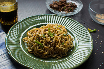 overhead view of scallion noodles on a green plate, top view of onion ramen noodles