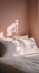 Soft sunlight streams through a window, casting leafy shadows on crisp white bedding and a blush-pink wall in a minimalist bedroom