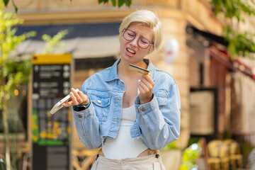 Shocked Caucasian woman trying to pay online shopping with smartphone blocked credit card. Annoyed...