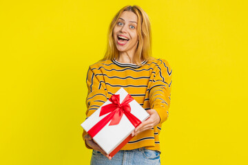 Positive smiling happy young woman presenting birthday gift box stretches out hands, offer wrapped...