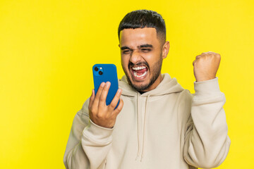 Happy excited Indian Arabian man guy use smartphone typing browsing shouting say wow yes found out...