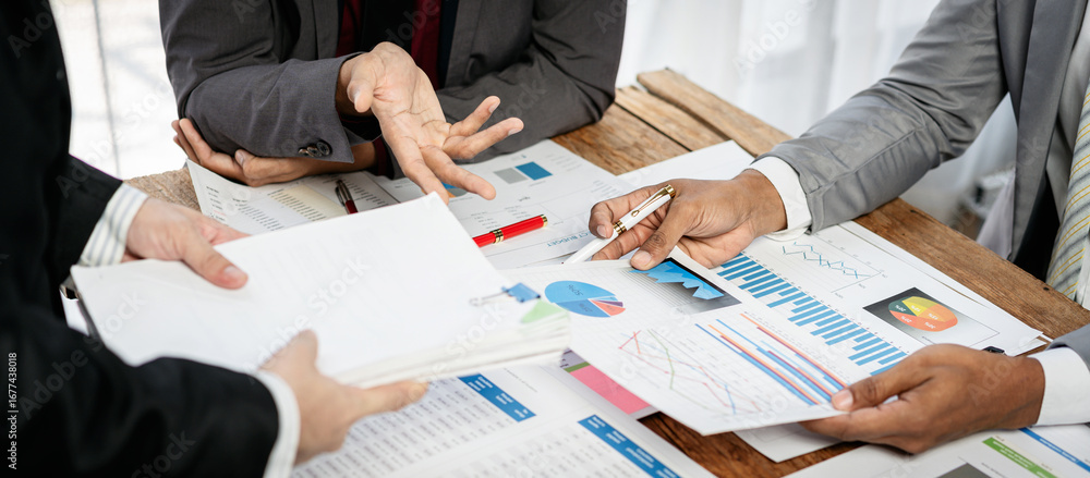 Poster three people are sitting at a table with papers and graphs in front of them