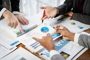 Three people are looking at a table full of graphs and charts