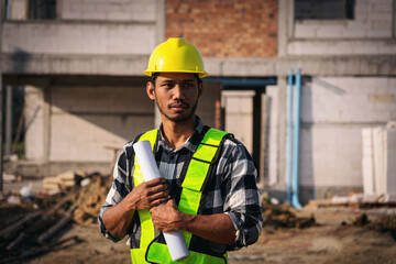 Asian Adult Construction Worker Holding Blueprint at Building Site Project with Yellow Hard Hat and...