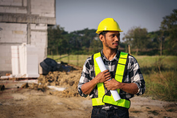 Asian Construction Worker with Blueprint on Site Safety Gear Young Asian Man Engineer Inspector...