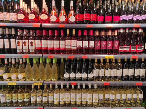 Bottles of white and rose wine on supermarket shelf in Malaga, Spain - January 1, 2024. Modern retail environment and consumerism, ideal for themes of commerce, shopping, and alcoholic beverages.